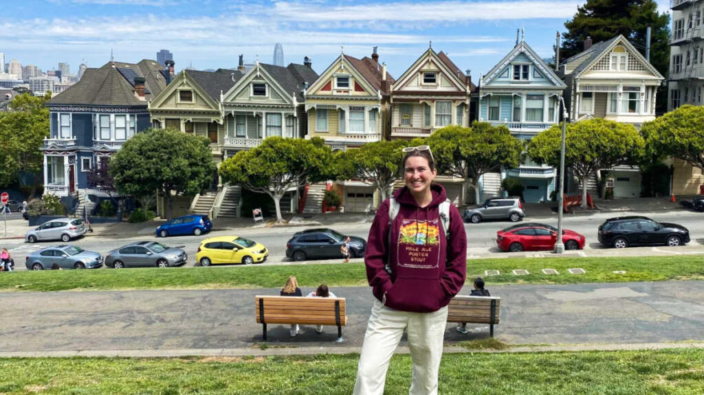 The author Laura McFarland, posing for a photo in front of the Painted Ladies in Alamo Square Park