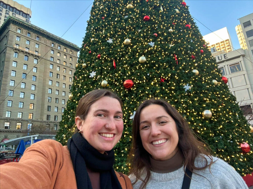 The author Laura and her partner taking a photo with the huge Christmas tree in the background at the Union Square
