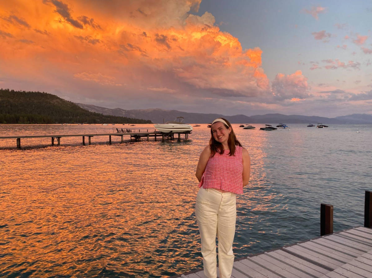 The author Laura McFarland, posing for a photo with a scenic view of the sunset at Lake Tahoe