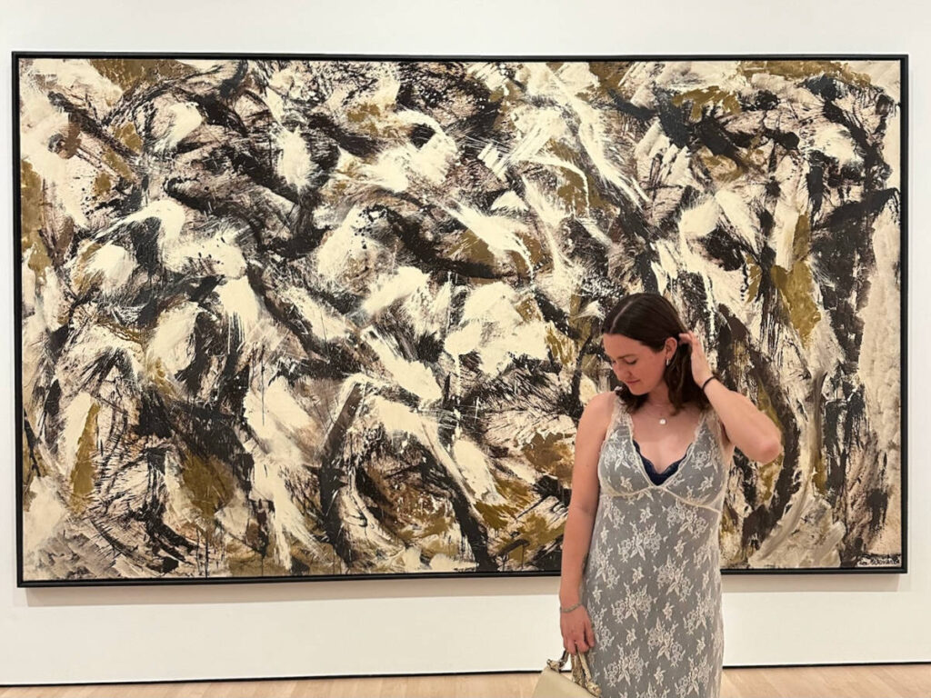 The author Laura McFarland posing in front of a Jackson Pollock piece at the MOMA