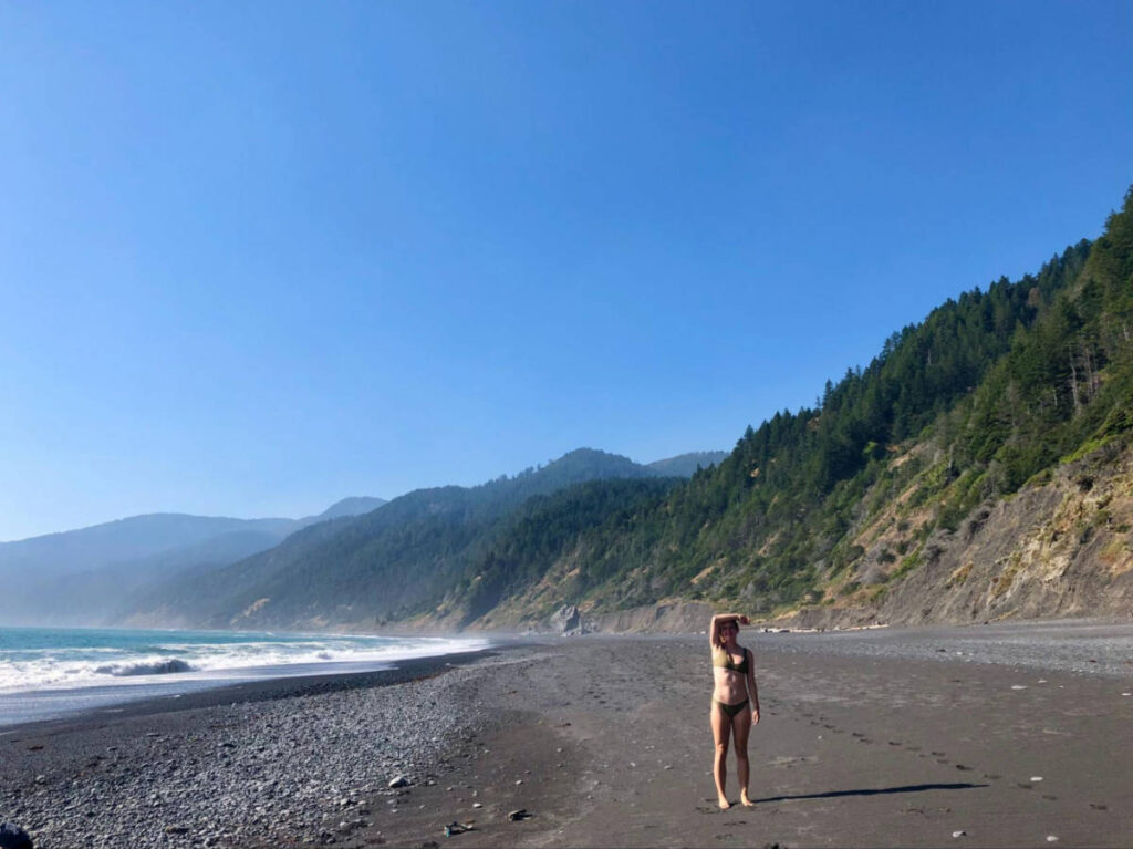 The author Laura McFarland posing for a photo on the Lost Coast with scenic mountain views