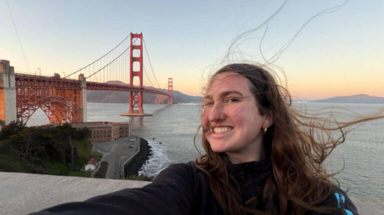 The author Laura McFarland, smiling for a photo with the view of the Golden Gate Bridge