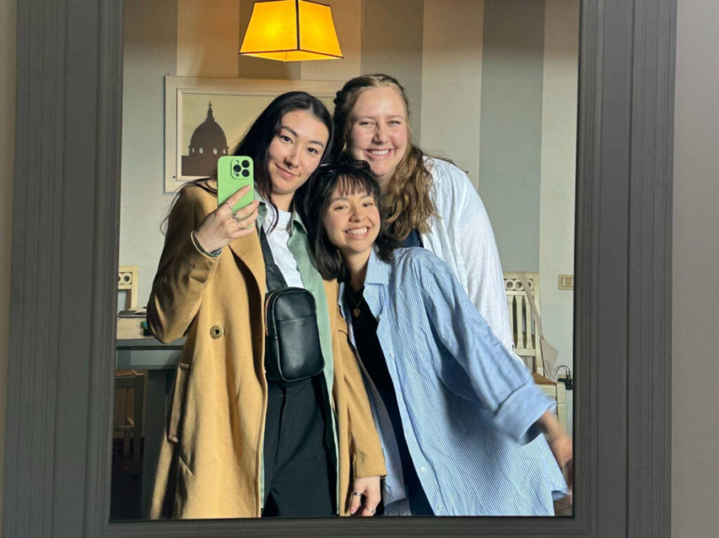 The author Lea Rose Allbaugh and her friends smiling for a photo in front of the mirror