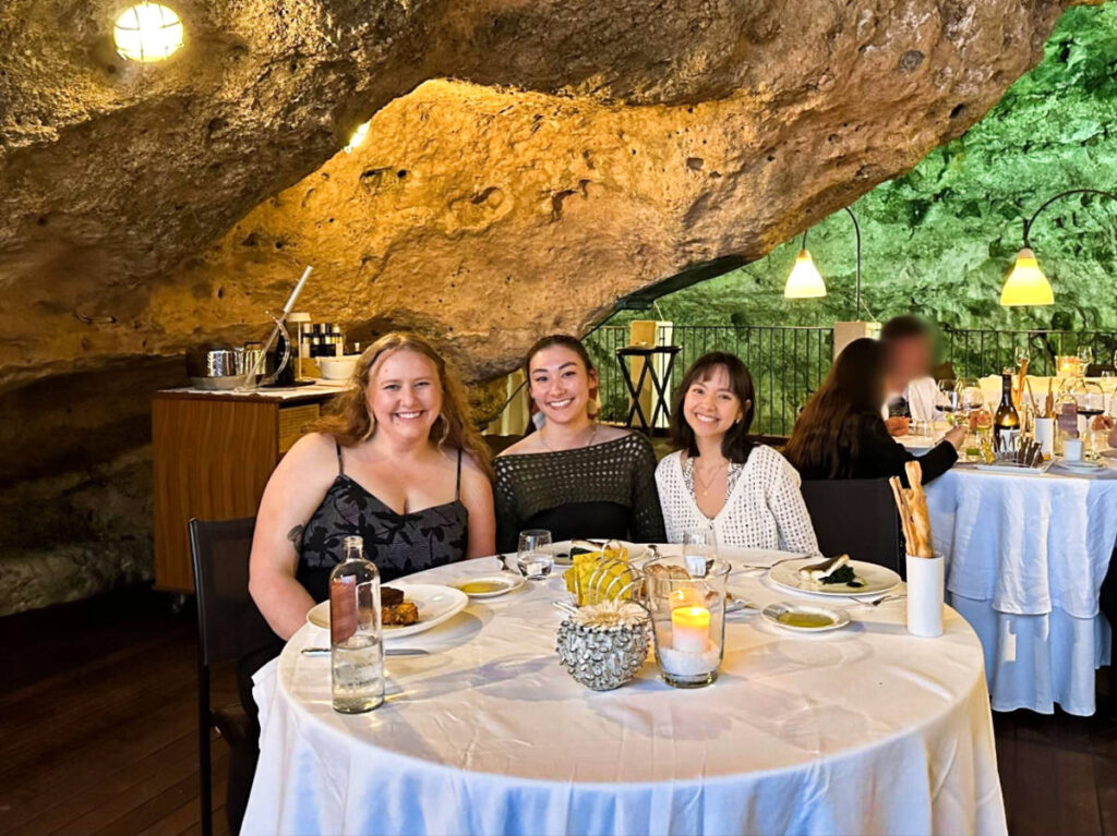 The author Lea Rose Allbaugh and her friends, smiling for a photo at the Grotta Palazzese