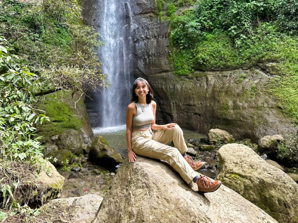 The author Lea Rose Allbaugh, sitting on the rock in front of the falls at the Atitlán Nature Preserve