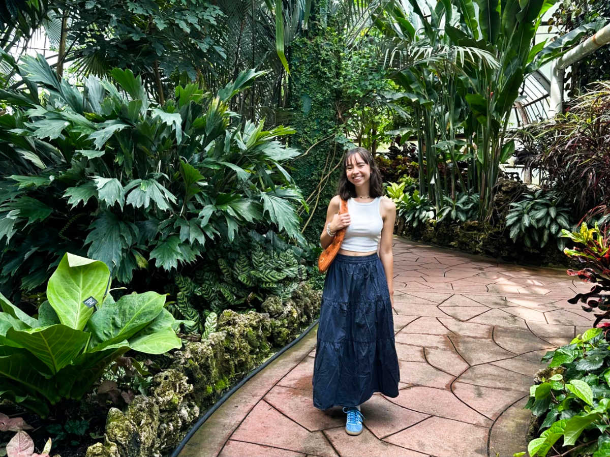 The author Lea Rose Allbaugh, posing for a photo in the middle of a pathway surrounded by greenery in Lincoln Park Conservatory