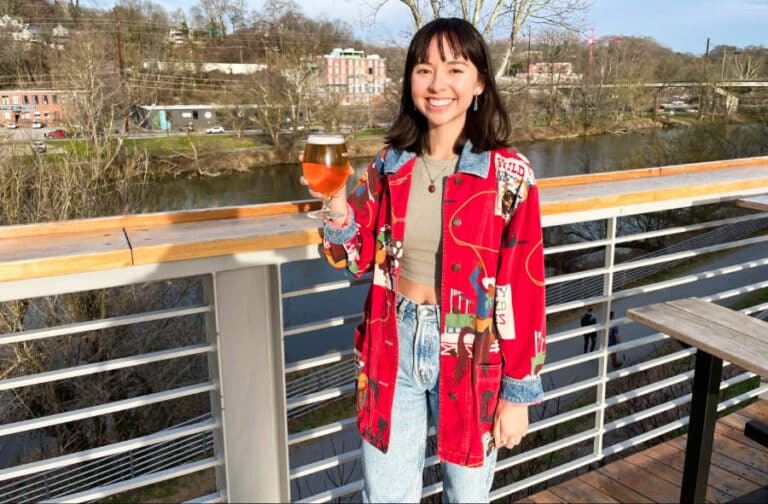 The author Lea Rose, posing while holding a glass of New Belgium’s Fat Tire beer