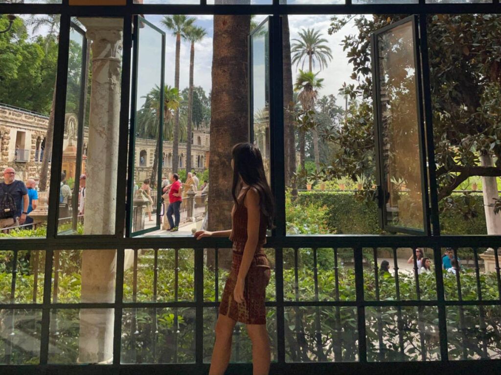 Author Lea Rose gazing out the window at Royal Alcázar of Seville