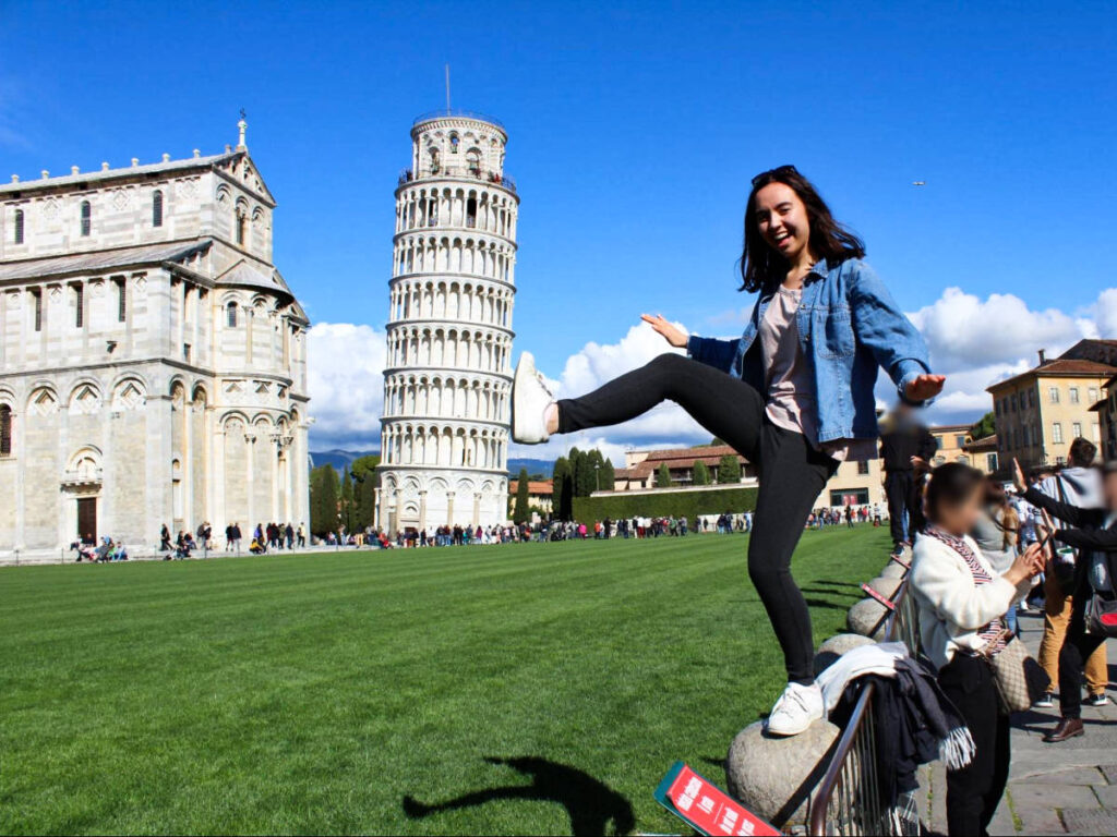The author Lea Rose taking a photo with the leaning tower of Pisa