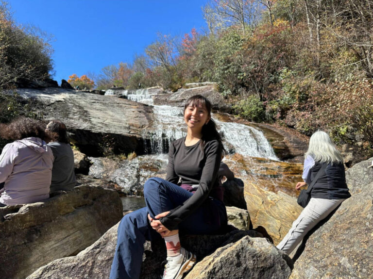 The author Lea Rose Allbaugh, sitting on the huge rocks at the Lower Falls at Graveyard Fields