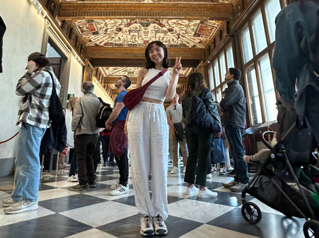 Author Lea Rose posing for a photo and showing a peace sign inside Uffizi Gallery