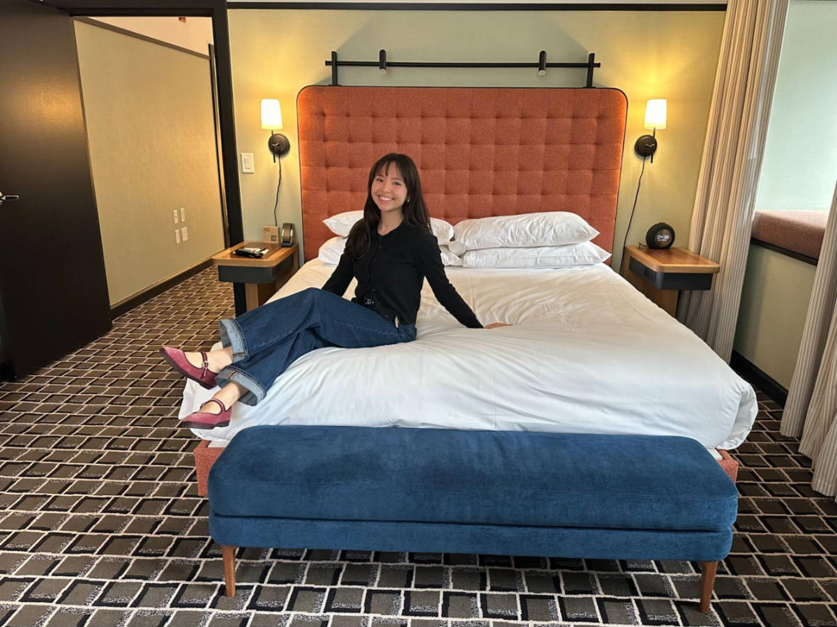 The author Lea Rose Allbaugh, sitting on the bed in a King Suite at the L7 Chicago by Lotte