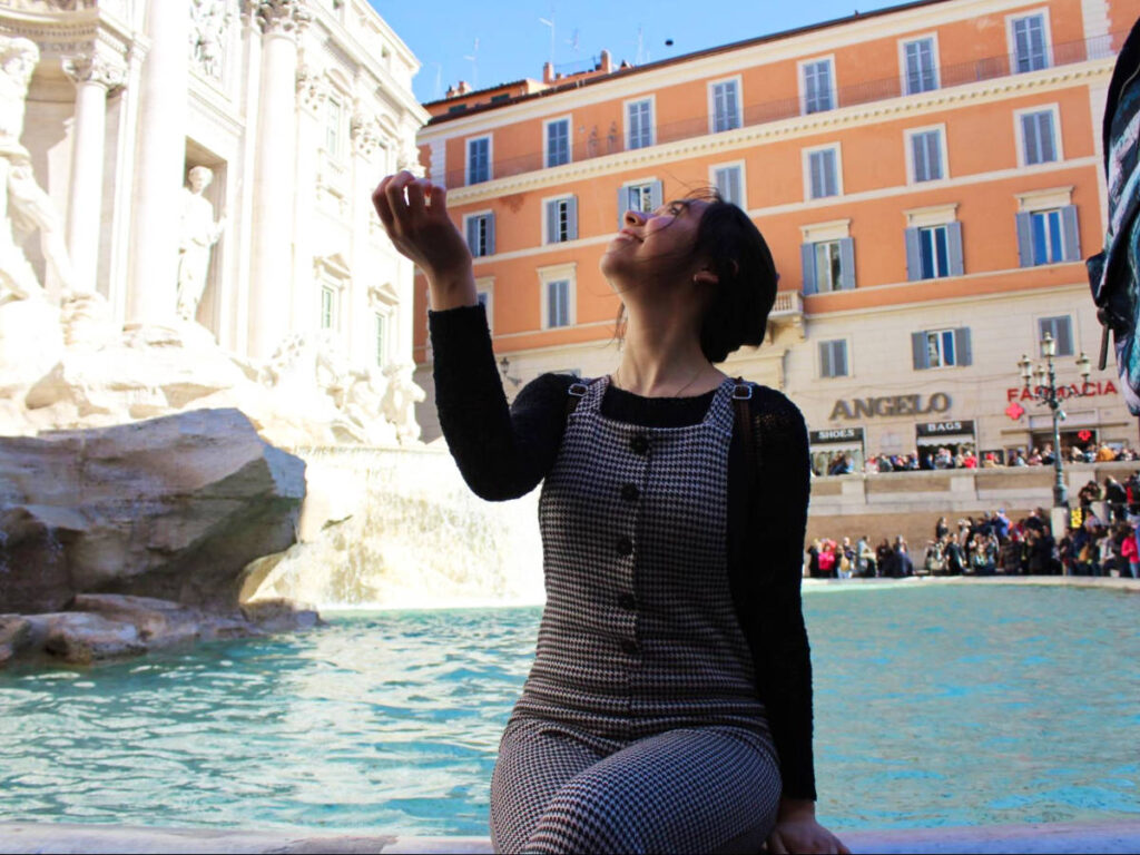The author Lea Rose tossing a coin in the Trevi Fountain
