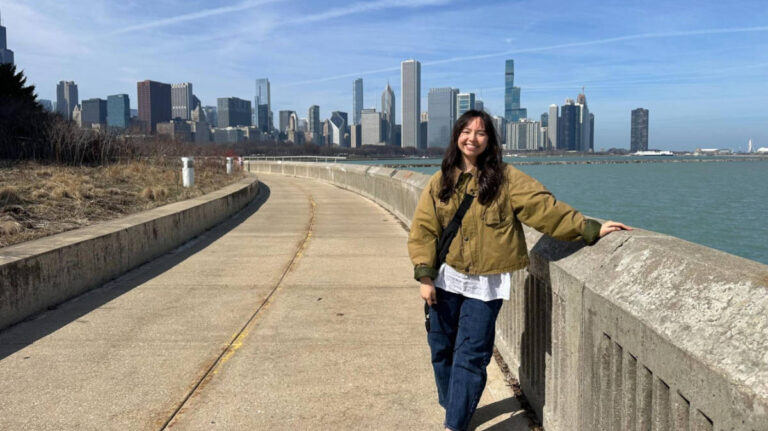 The author Lea Rose Allbaugh, smiling for a photo with the Chicago skyline in the background