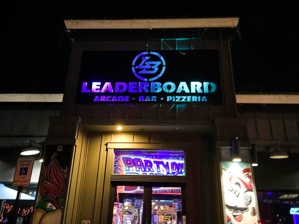 View of the illuminated signage of the Leaderboard Arcade Bar & Pizzeria at night