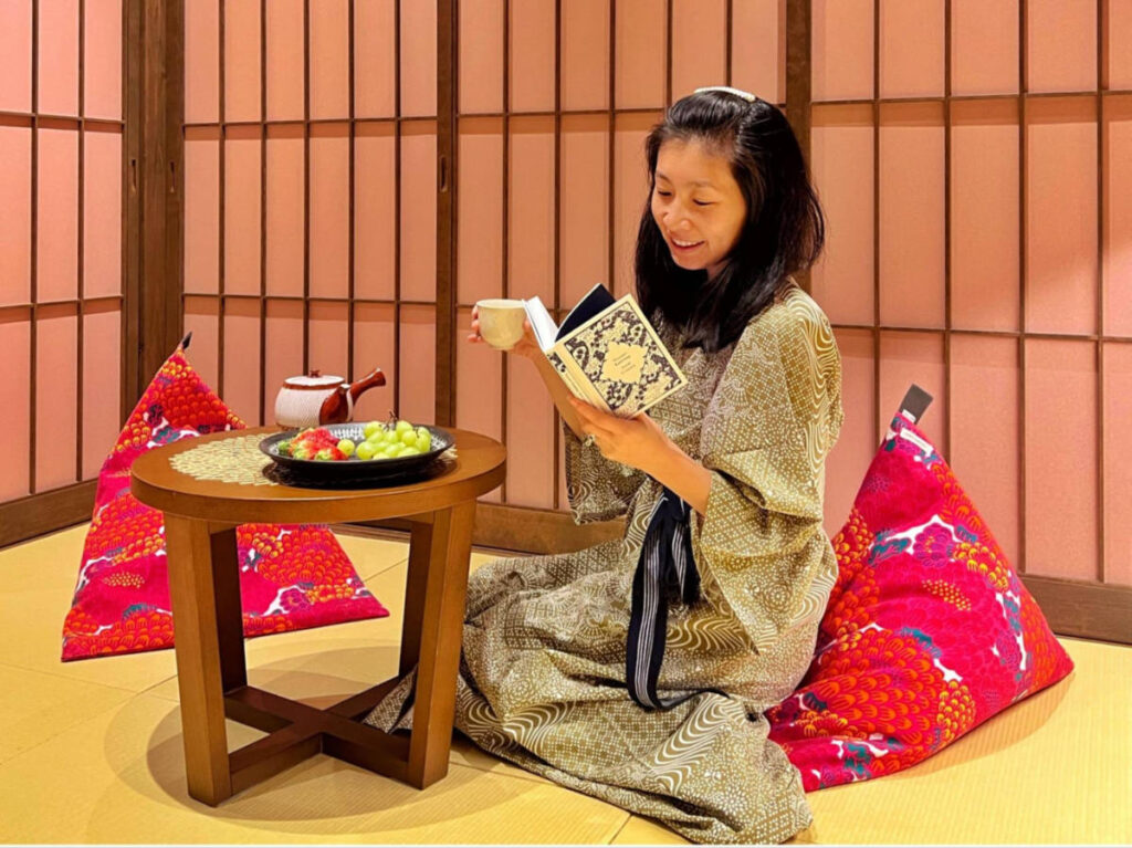 The author Lia Tee, reading and drinking a tea in the traditional tatami room of Kagabi Temari Machiya