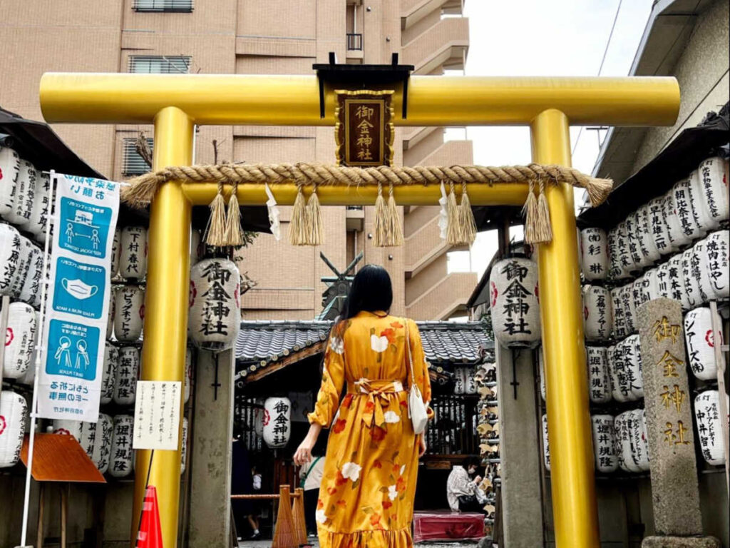 The author Lia Tee, posing for a photo in front of the golden torii gate in Mikane Jinja