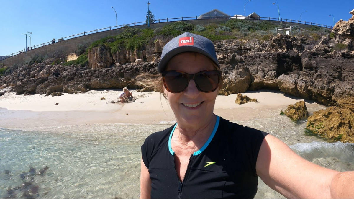 The author Lisa Ikin, smiling for a photo at a snorkeling beach on a sunny day