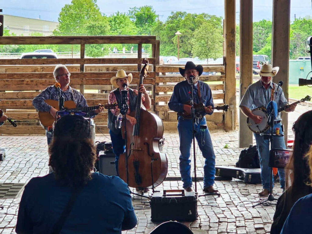 Men performing live with string instruments at the Fort Worth Stockyards Station
