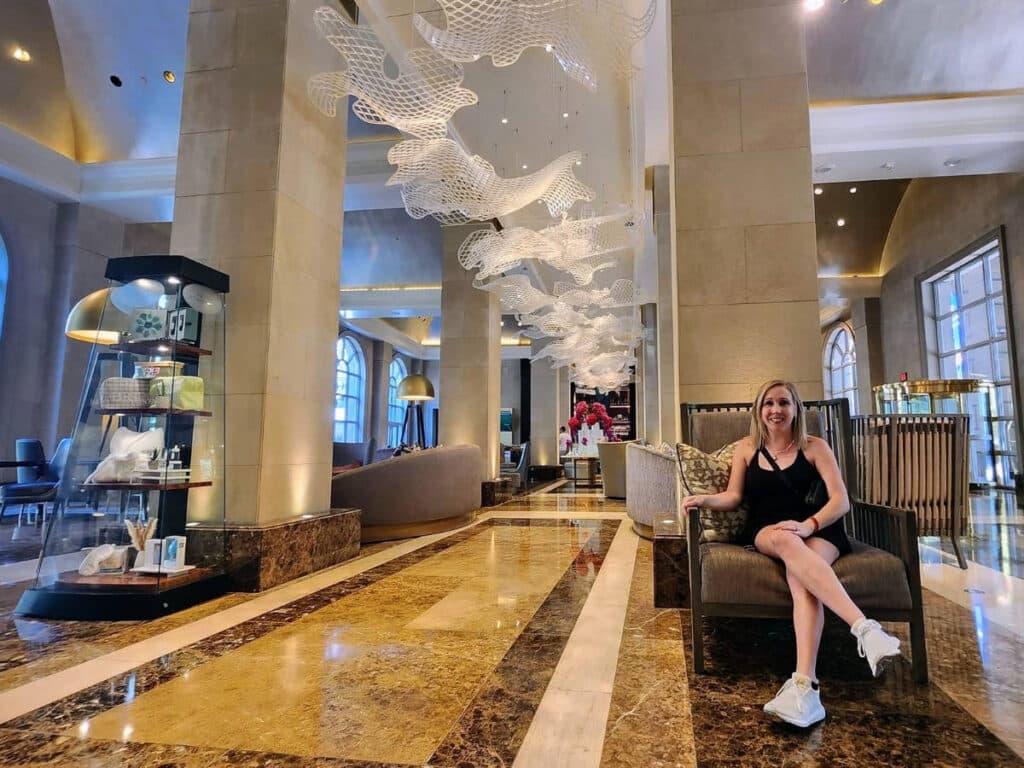 The author Sarah Heath sitting on a chair in the lobby of Hotel Crescent Court