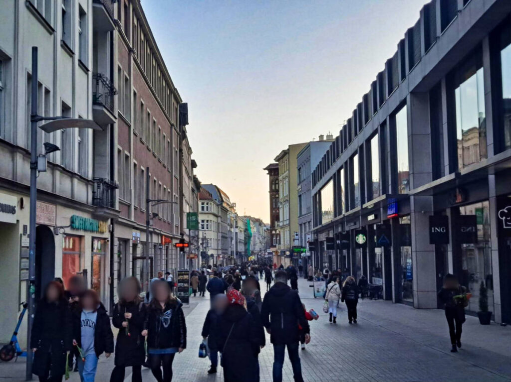 A group of people walking down a bustling city street with the European buildings around