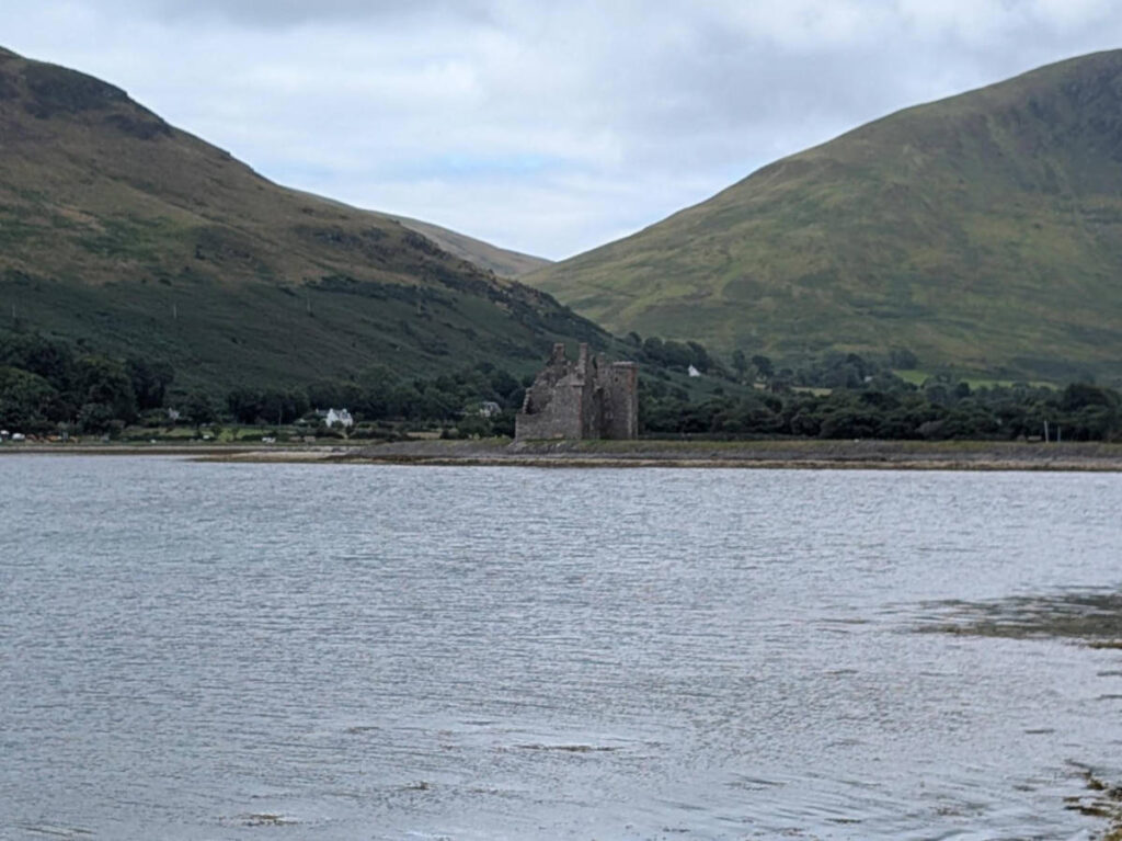 View of the Lochranza Castle below the lush mountains in the bay