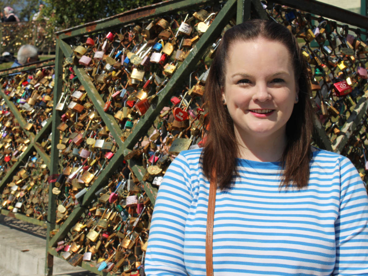 The author, Rachel Kapelke Dale smiling for a photo in front of the locks of love around Sacré-Coeur