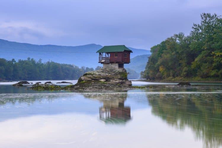 Lonely house on a river above a rock