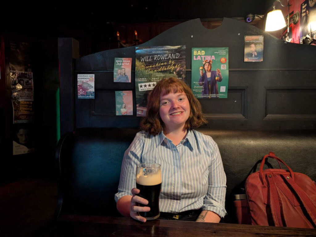 The author Louise Wylie, smiling for a photo with a pint of beer in Banshee Labyrinth bar