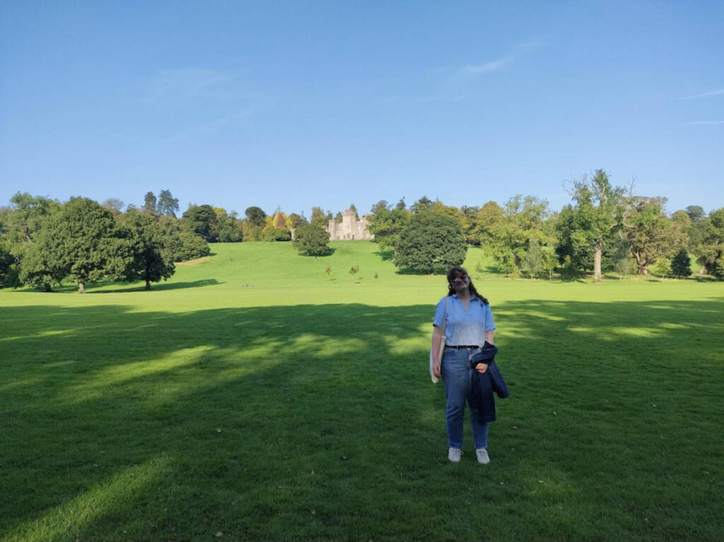 The author Louise Wylie posing for a photo under the shade at a vast green field