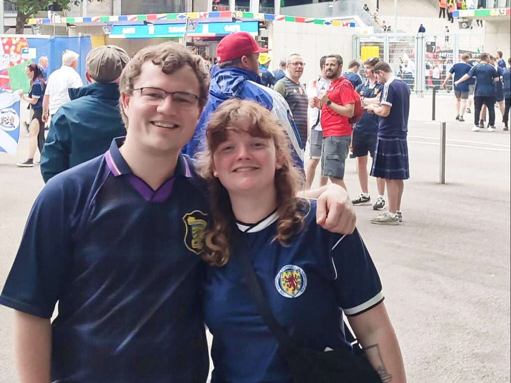 The author Louise Wylie and her partner Calum, posing for a photo while wearing their Scotland football shirts