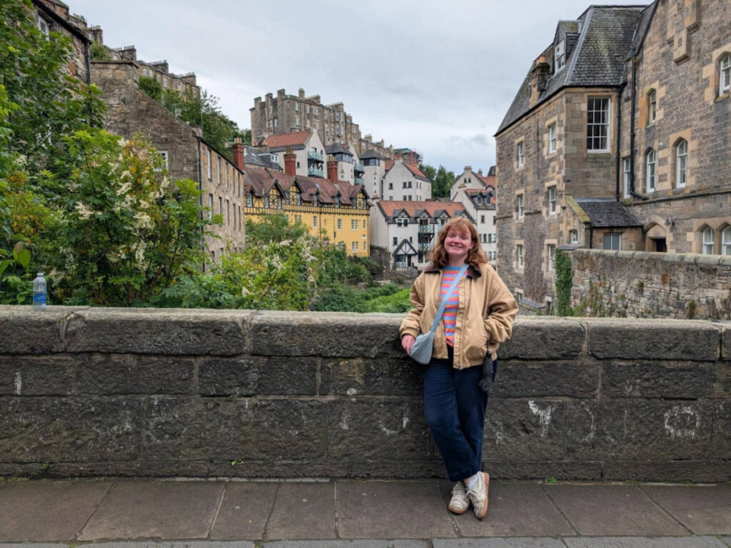 The author Louise Wylie smiling for a photo with an iconic view at Deans Brae Bridge