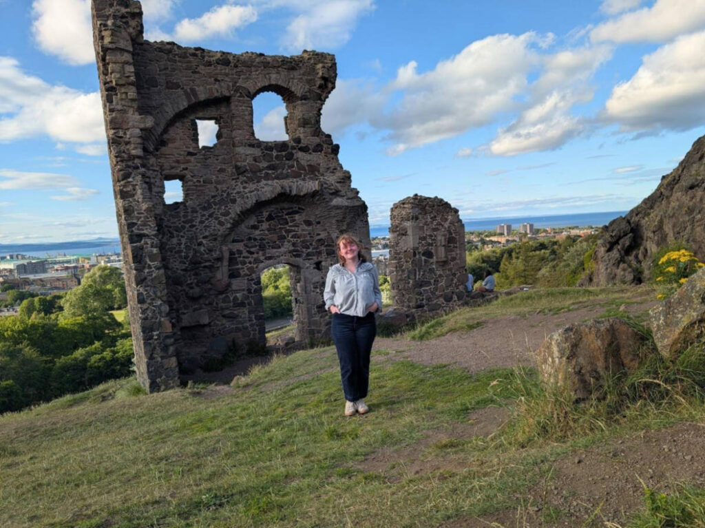 The author Louise Wylie smiling for a photo at the last surviving wall of St Anthony’s Chapel