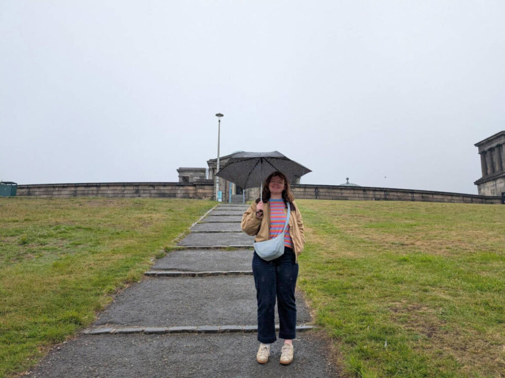 The author Louise Wylie, holding an umbrella under the rain in Edinburgh