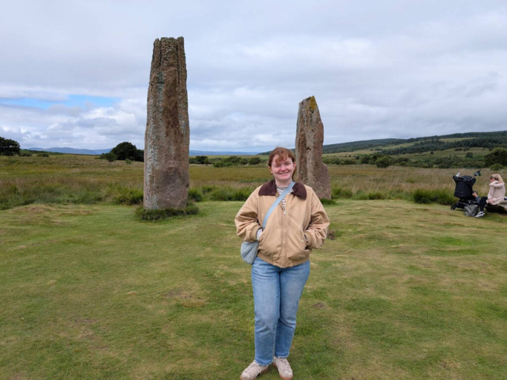 The author Louise Wylie, standing in front of the standing stones on the Isle of Arran