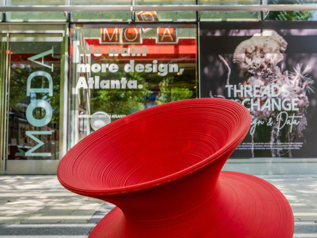A red spinning chair sculpture sits on the sidewalk outside the Museum of Design Atlanta (MODA)