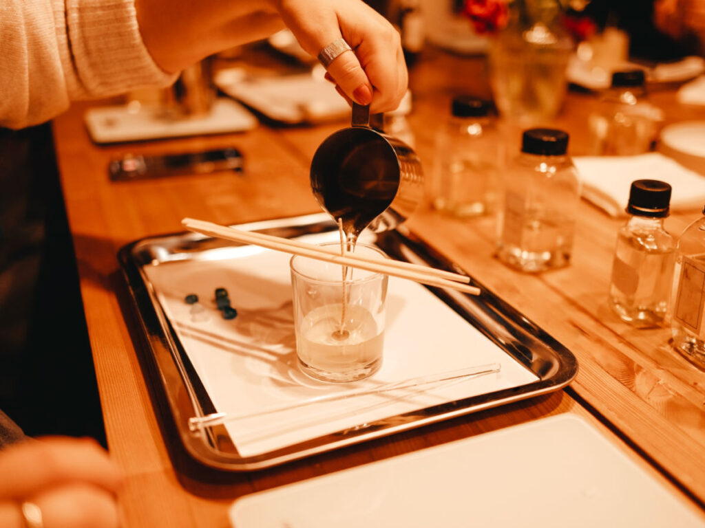 A person pouring melted wax into glass