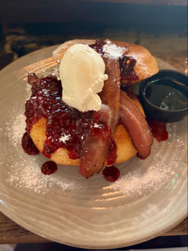 A Malted deep dish pancakes with bacon and blueberry compote served on a plate at The Riding House Café