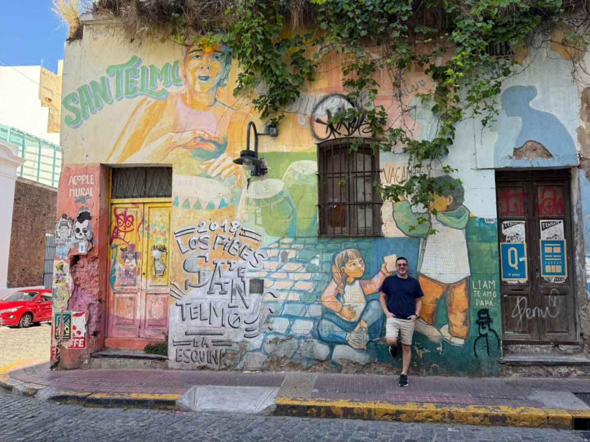 A man posing for a photo against the colorful street art in San Telmo