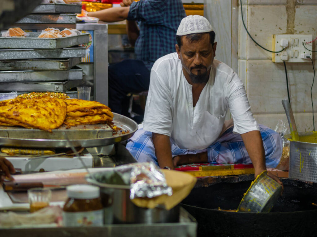 A man frying malpuas along the Mohammed Ali Road