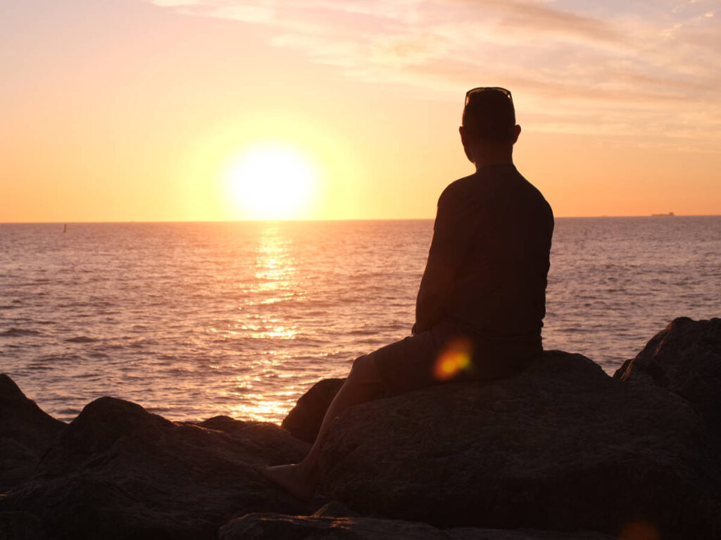 A man admiring the scenic view of the beach at sunset