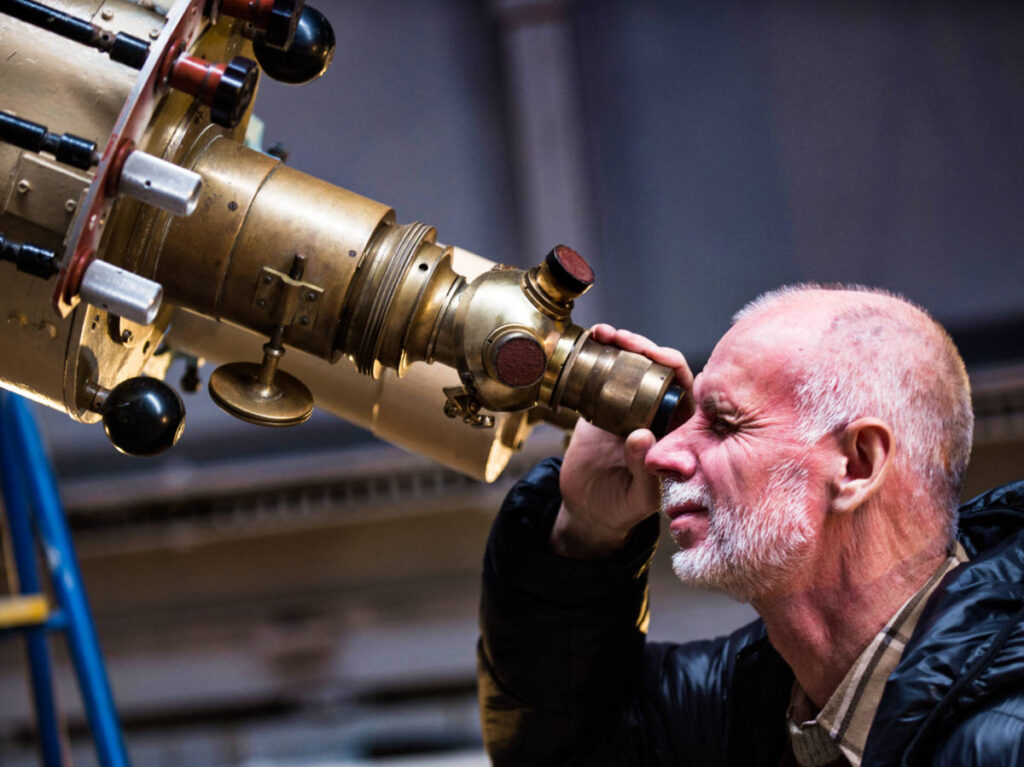 A man looking through a vintage telescope