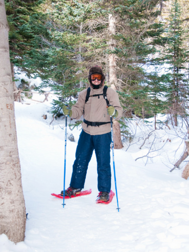 A snowshoer posing for a photo under the pine tree in winter