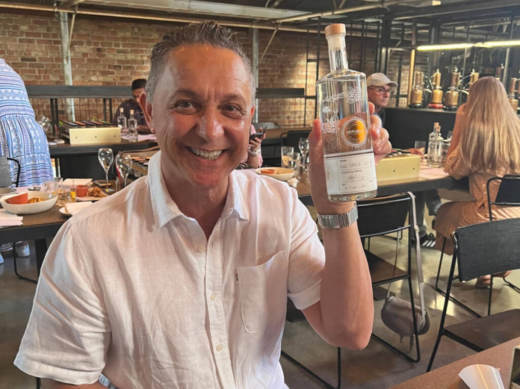 The author's partner holding a bottle of gin at the Republic of Fremantle Distillery