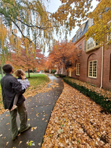 A man carrying a toddler at the Whitman College surrounded by fall foliage