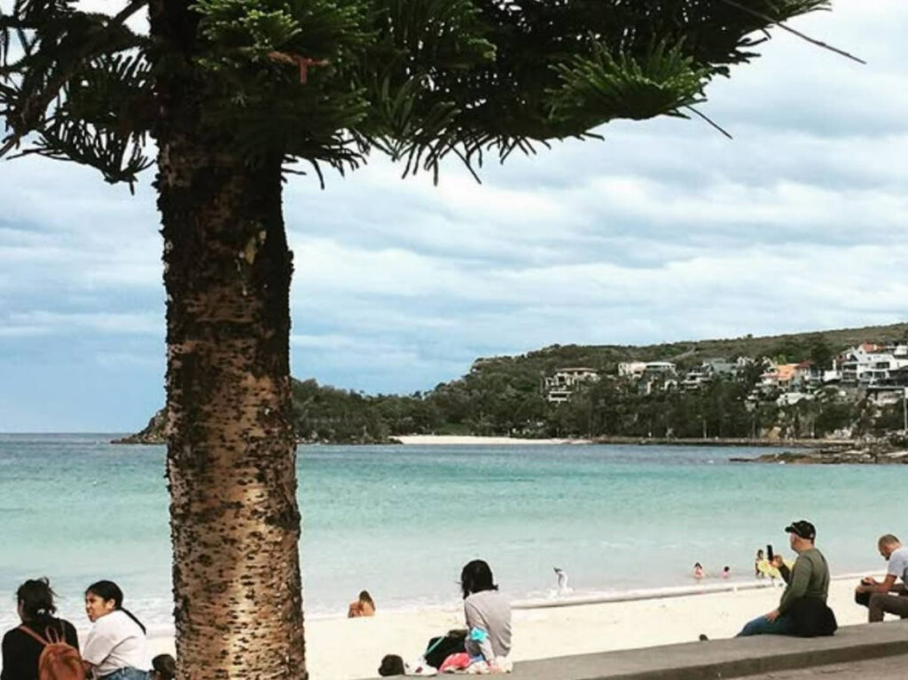 People sitting along the Manly Beach Esplanade
