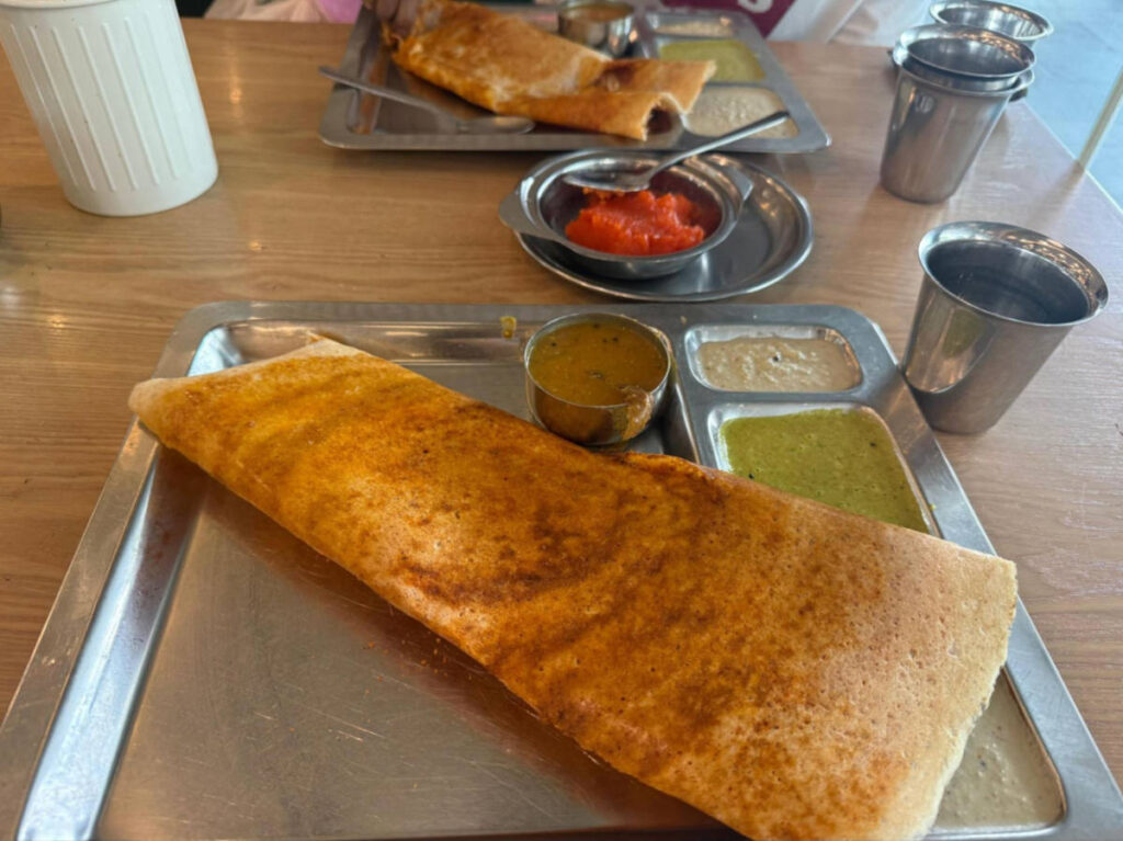 A tray with masala dosai with chutneys at Saravanaa Bhavan
