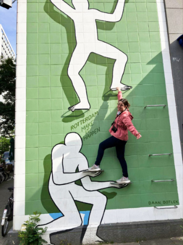The author Meg O’Connor smiling for a photo while climbing on a street art in Rotterdam, Netherlands