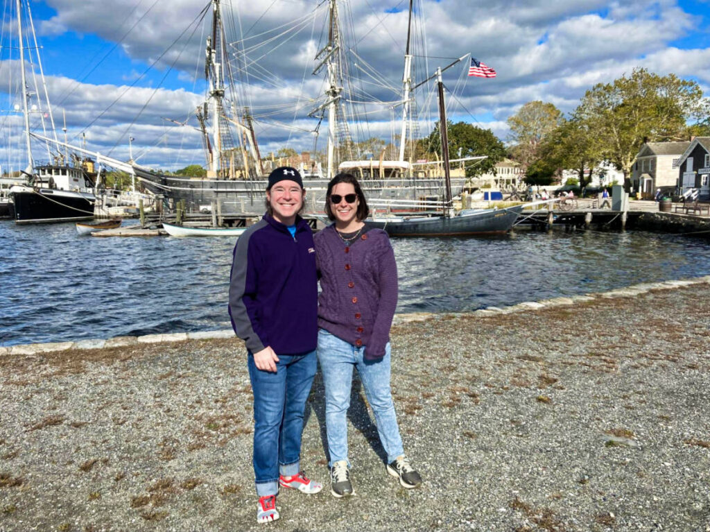 The author Meg O'Connor and her brother, posing for a photo near the docked boat in Mystic