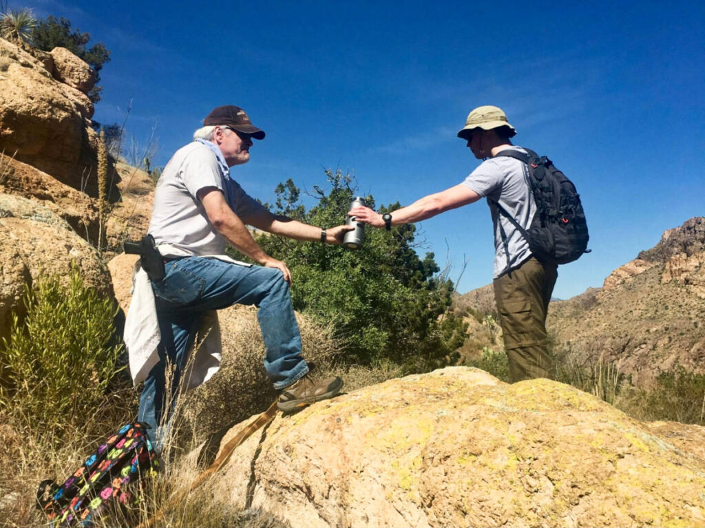 Two men sharing the bottled water on the trail